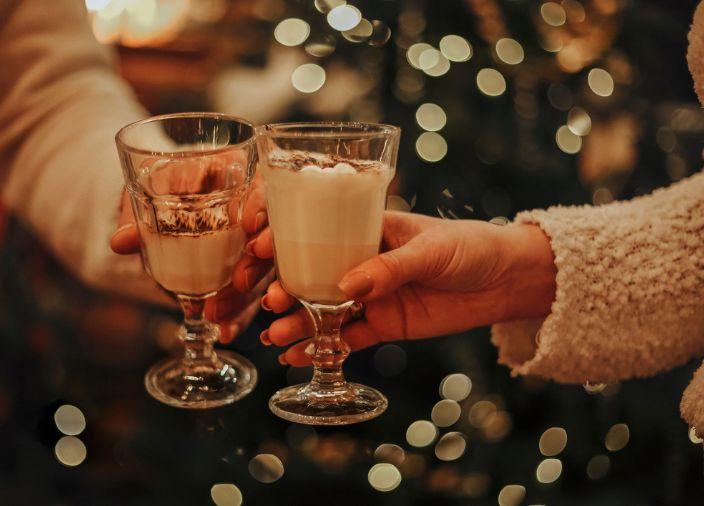 Zwei Cocktails werden vor einem Weihnachtsbaum angestoßen.