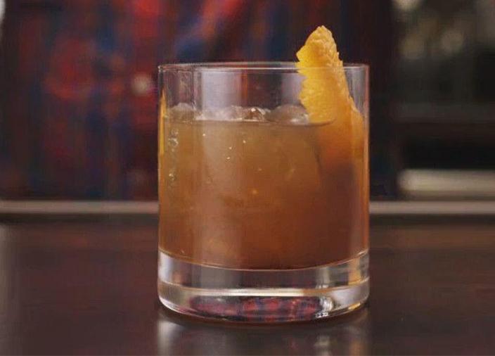 Un vaso highball con un cóctel Open Gate Posada con hielo triturado y rodajas de lima, sobre un fondo blanco transparente.