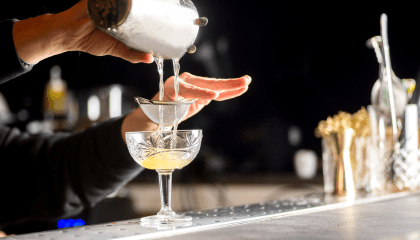 Bartendender usando un colador para servir un cóctel