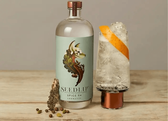 Botella de Seedlip Spice 94 en la mesa junto al cóctel 