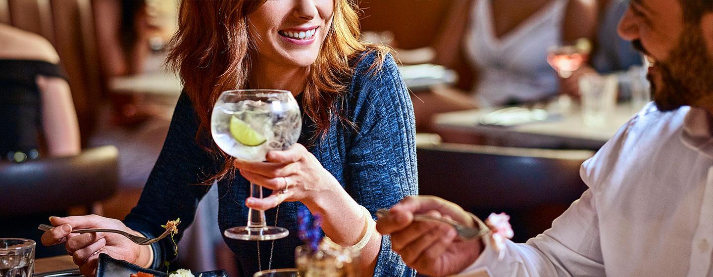 Woman holding a cocktail while speaking to a man
