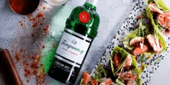 botella Tanqueray acompañada de un arreglo de comida