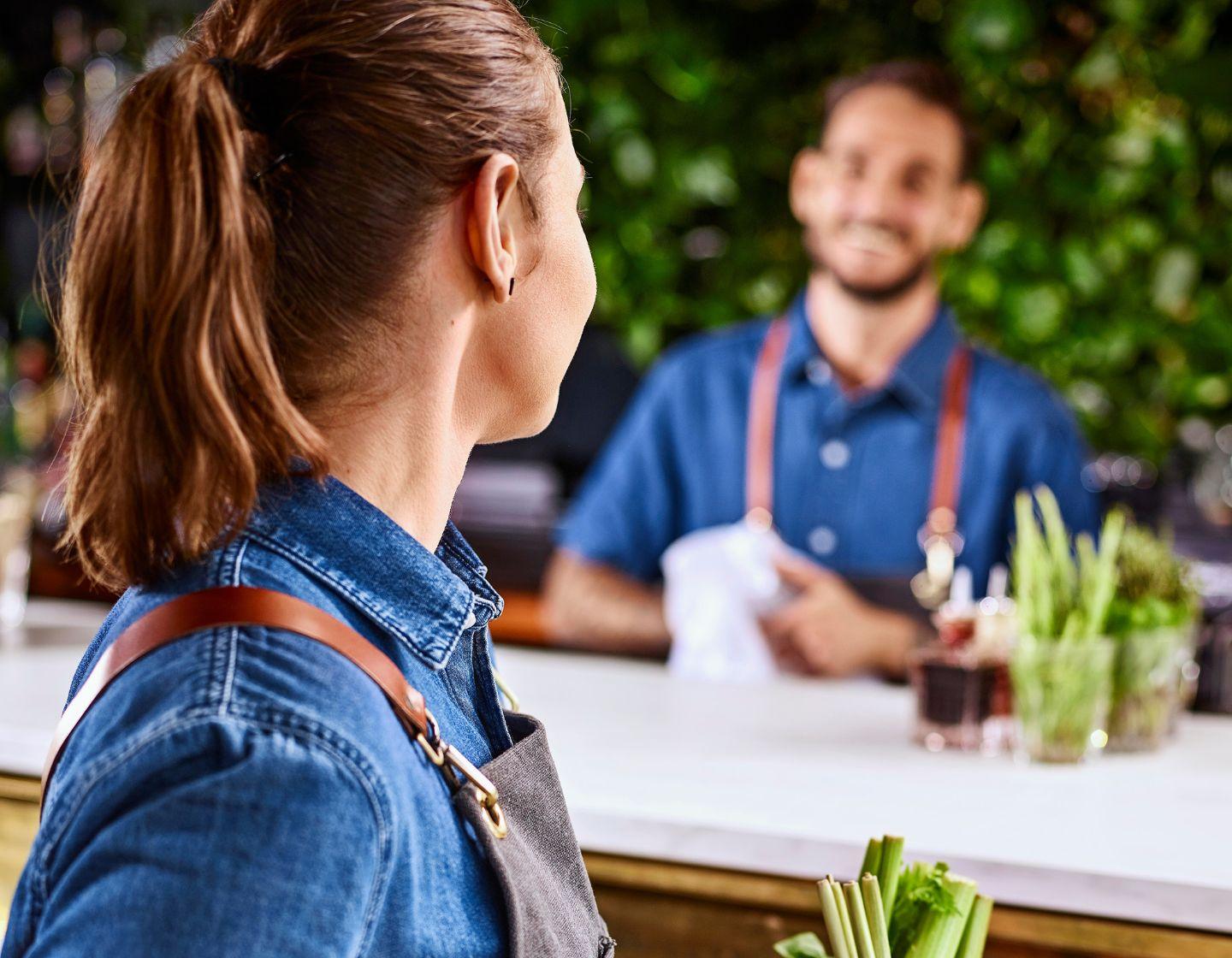 Dos bartenders hablan en el mostrador