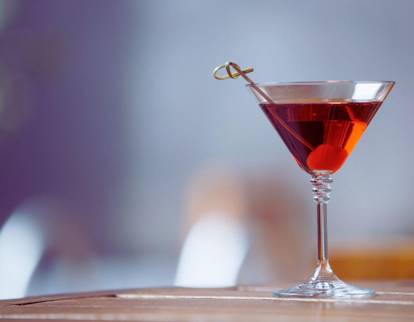 Red cokctail in cocktail glass with garnish.