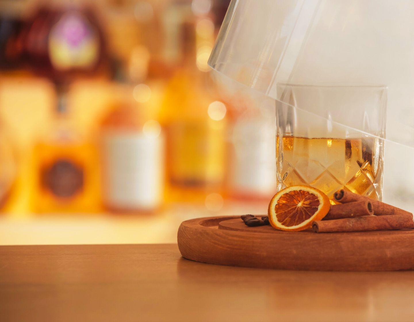 Un vaso transparente lleno de líquido con garnish de naranja seca.