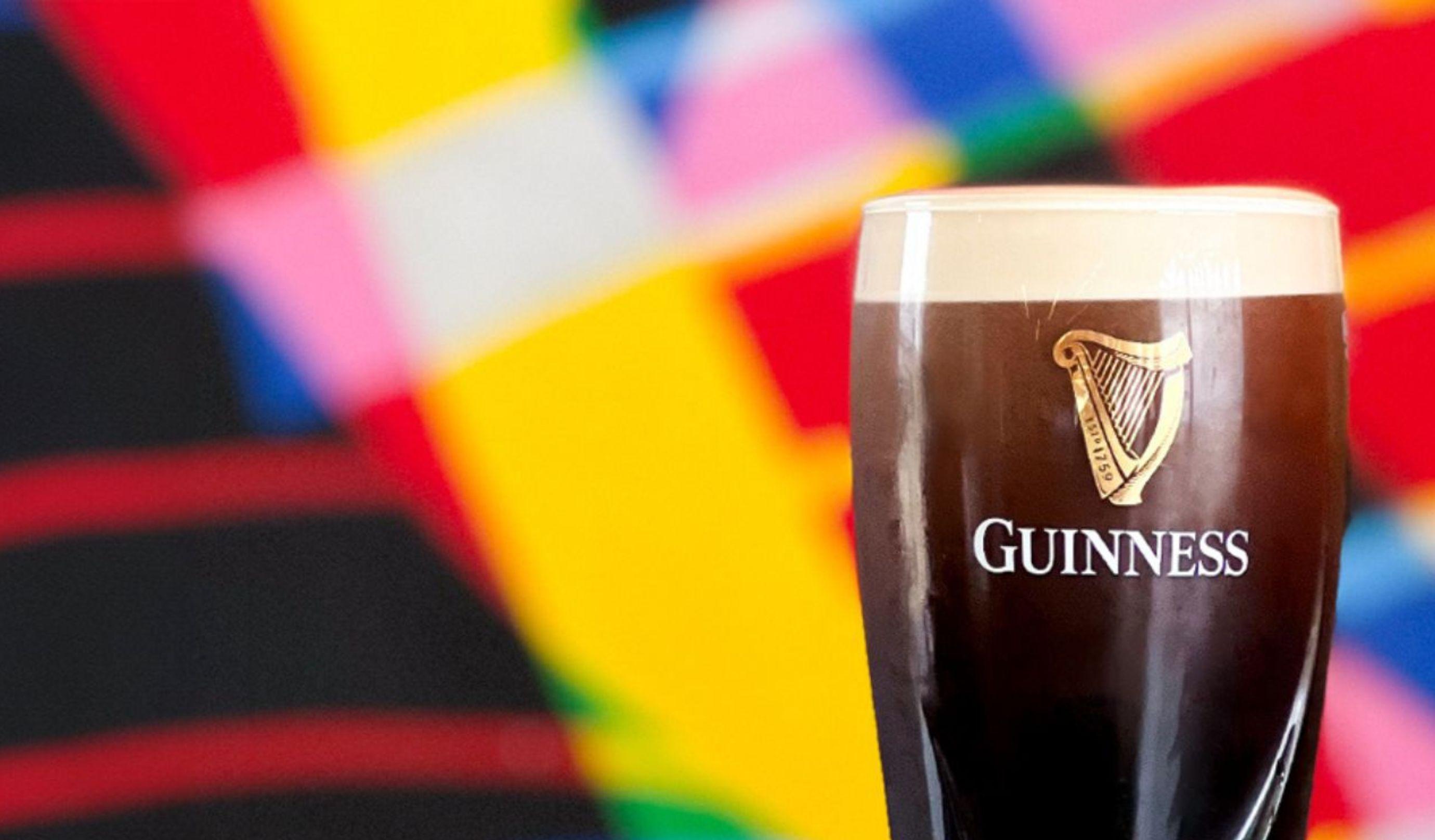Guinness in a branded glass with a colourful background.