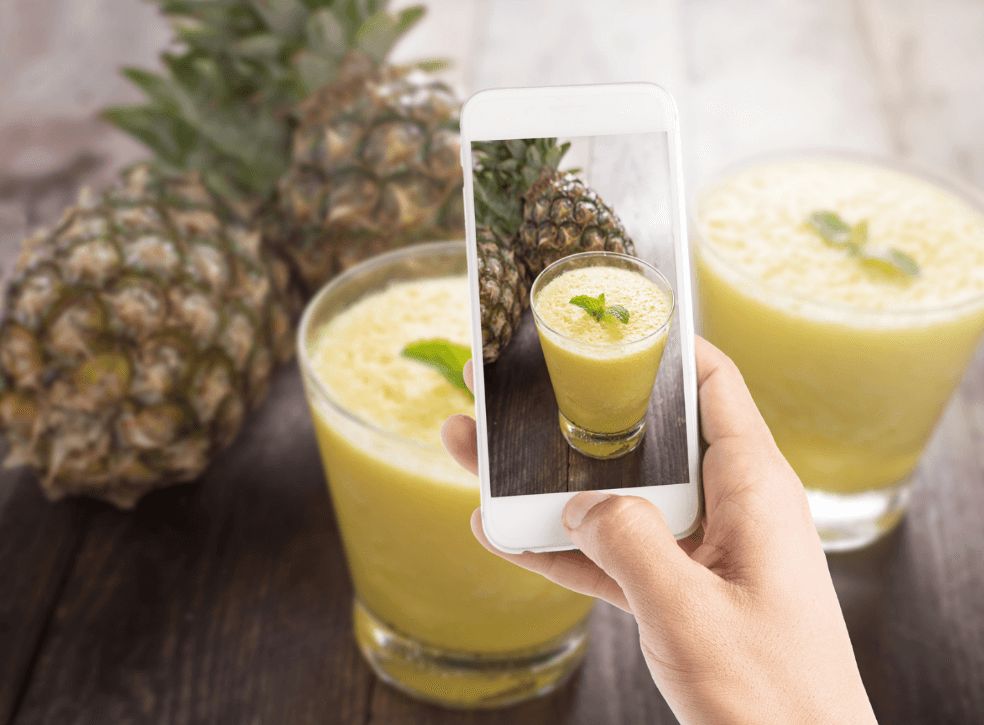 Bartender tomando una foto de una bebida con su teléfono