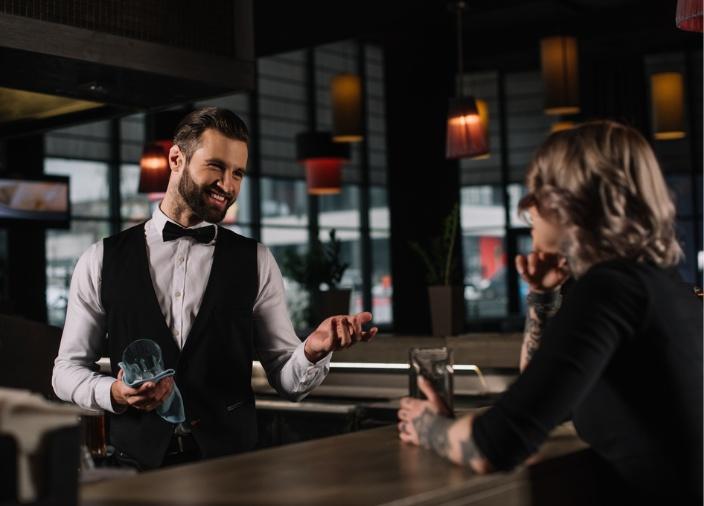 Un barman sonriendo a un cliente desde el otro lado de la barra