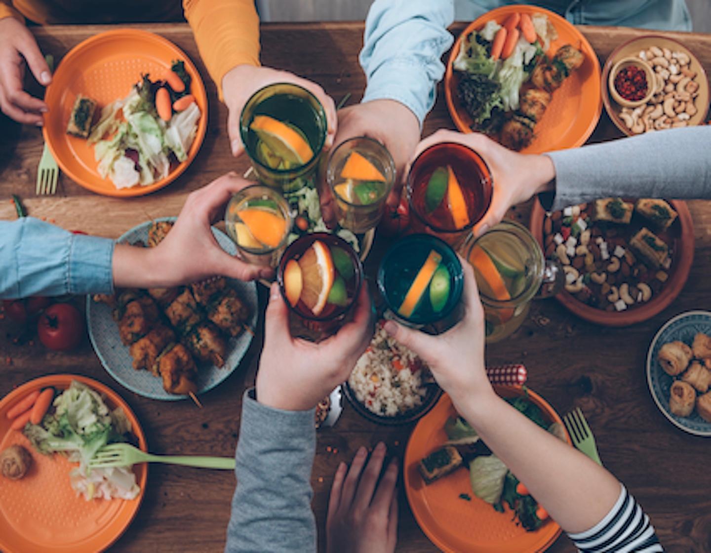 friends toasting drinks over food