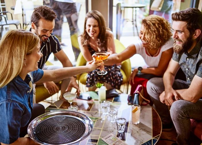 Bartender serving drinks to a table of smiling customers