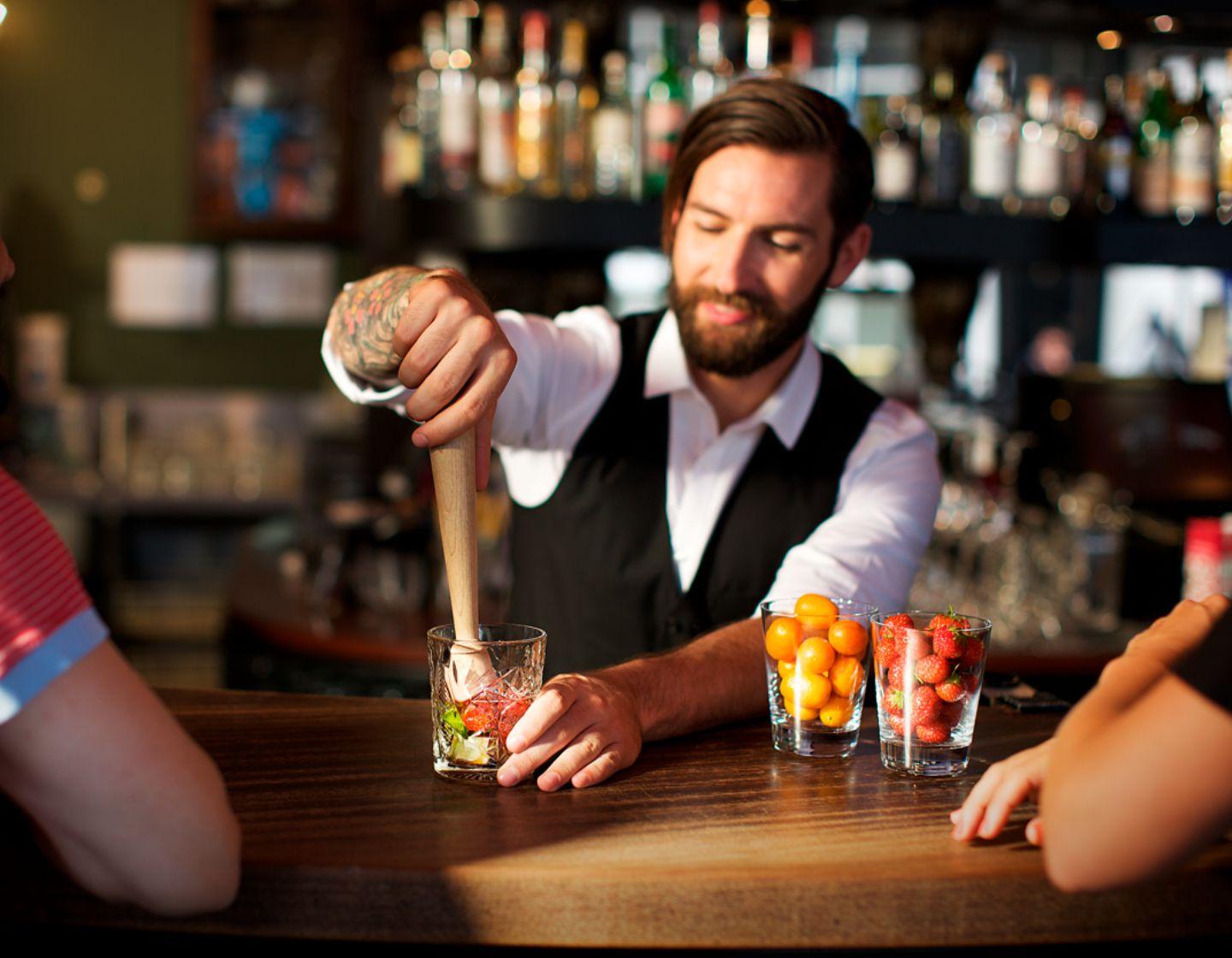 Ein Barkeeper muddelt an einer Bar