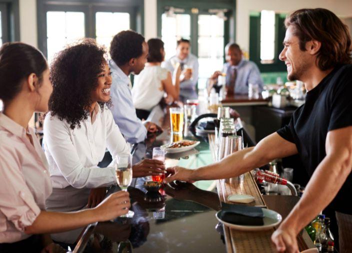 Un bartender sonriente sirviendo una cerveza.