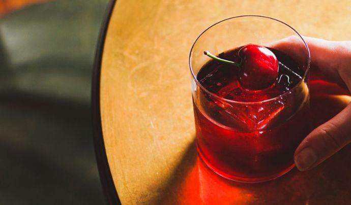 Un cóctel negroni con garnish de cerezas.