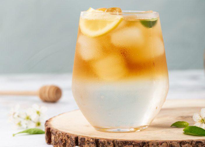 Mujer detrás de la barra vertiendo líquido en un cocktail jigger 