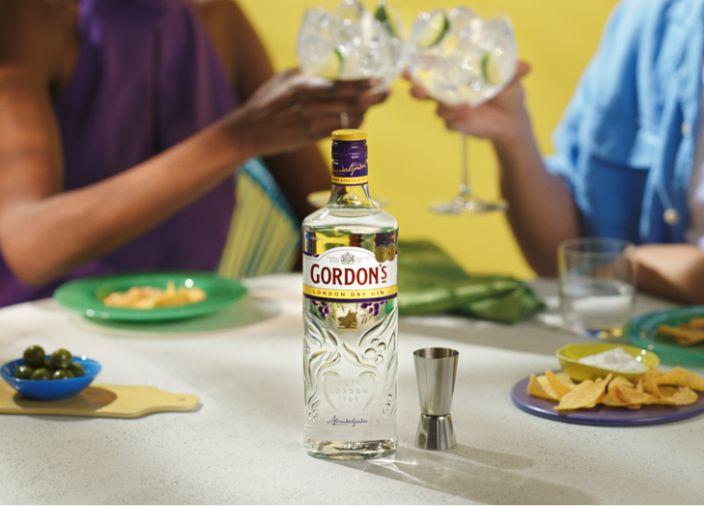 Two people with gin glasses with a Gordon's Export Gin bottle in the foreground.