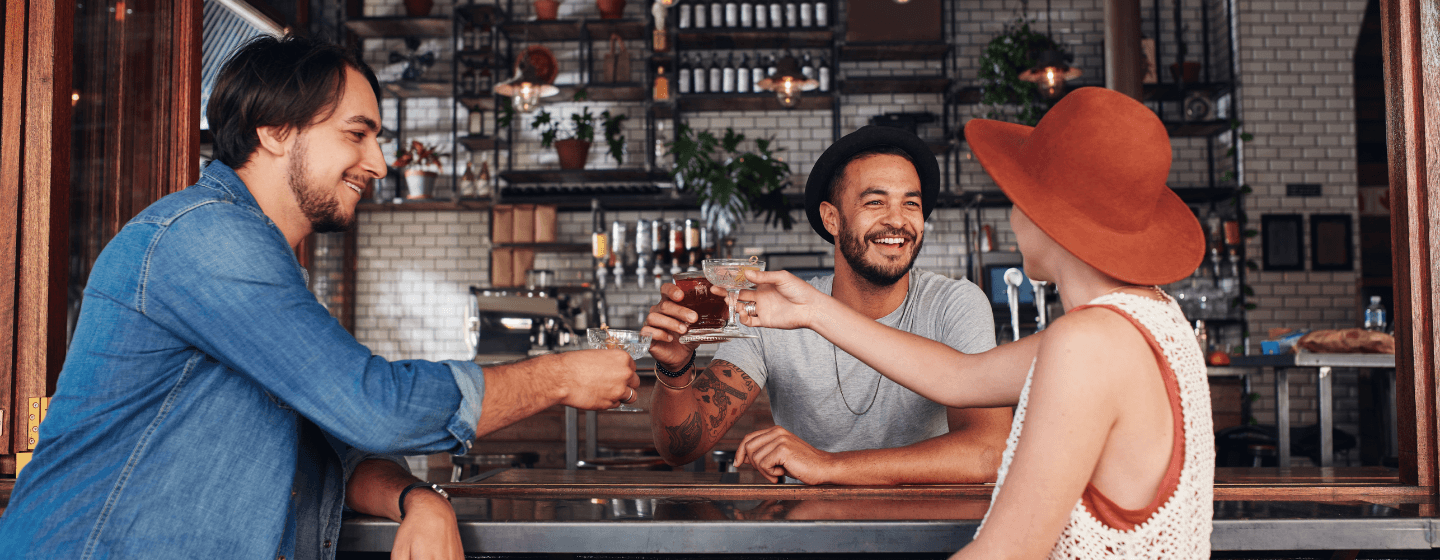 Bartender clinking drinks at the bar with customers