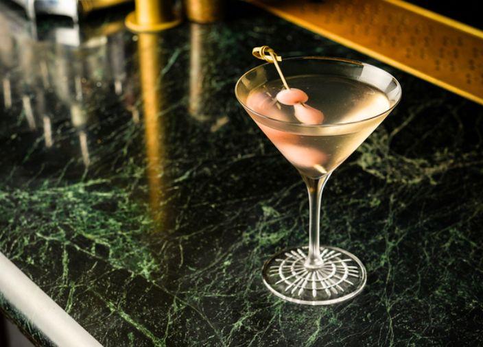 Un martini con garnish de pepinillos rosados.