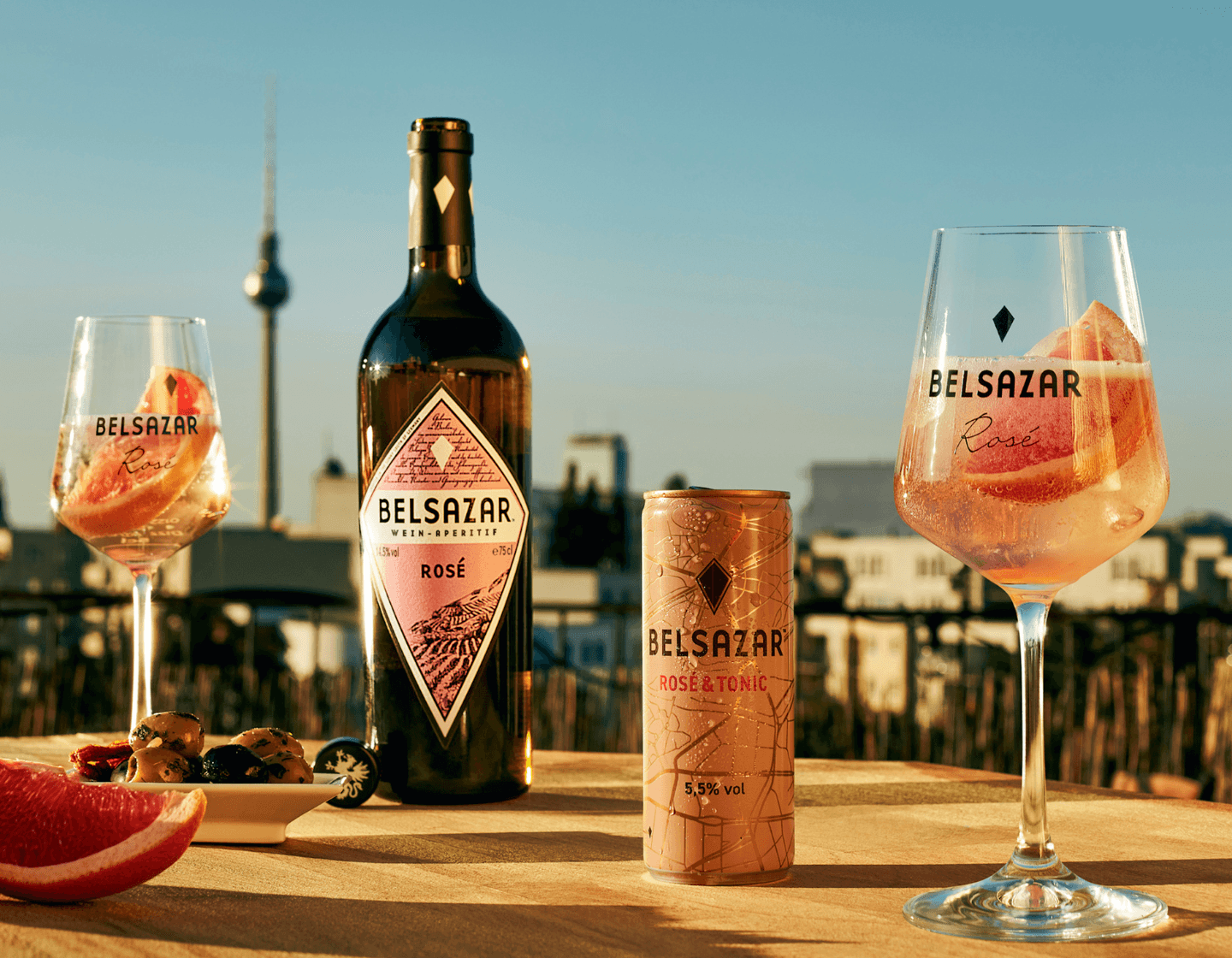 Bottle of Belsazar on table outside beside two wine glasses filled with cocktails 