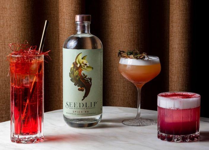 Seedlip bottle beside three expert alcohol-free cocktails 