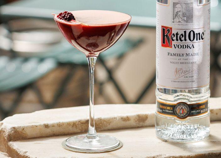Cóctel rojo acompañado de una botella de licor.