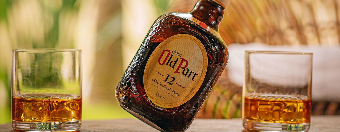 Bottle of Old Parr on table with cocktails