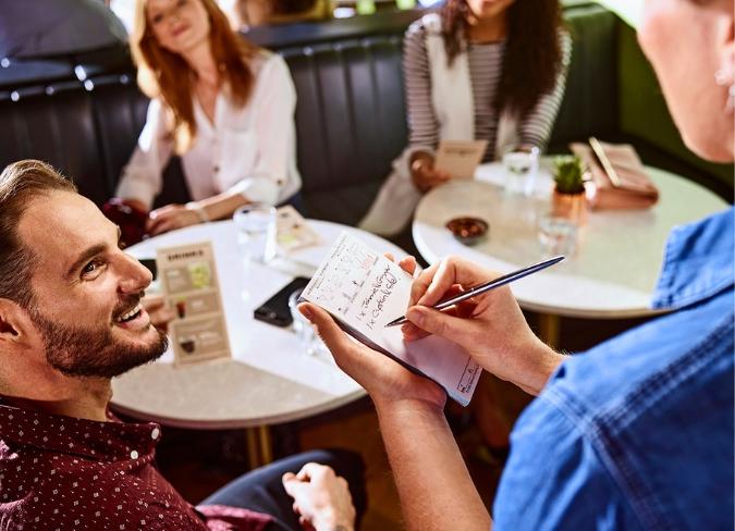 female staff taking customers orders at table