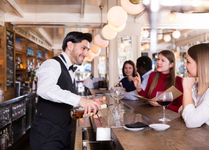 Bartender servindo drinks e sorrindo para os convidados