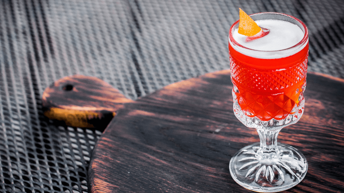 red cocktail on a wooden board.