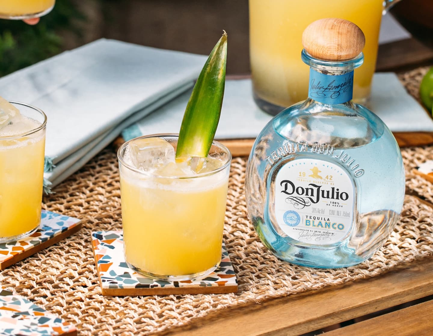 Bottle of Don Julio Tequila next to cocktails on a table