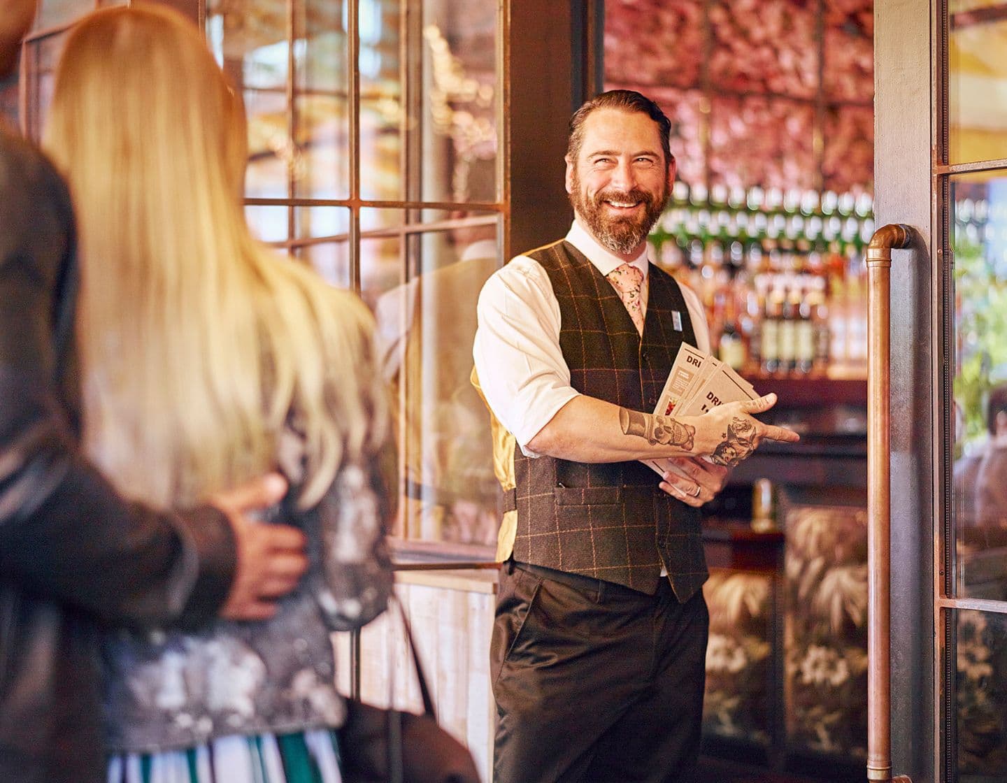Host greeting guests at the door with menus.