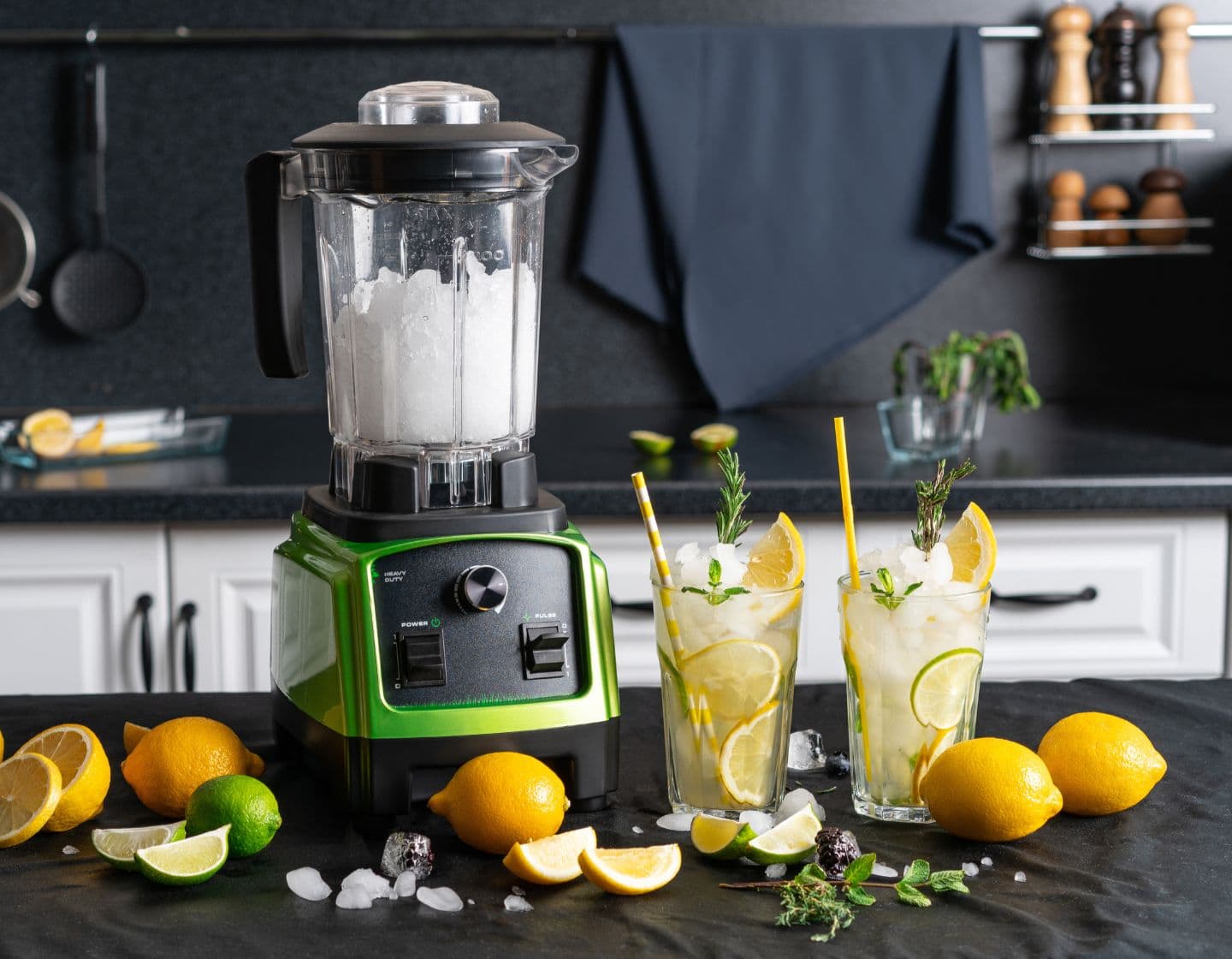 An electric blender on a bar surface with cocktails and lemons 
