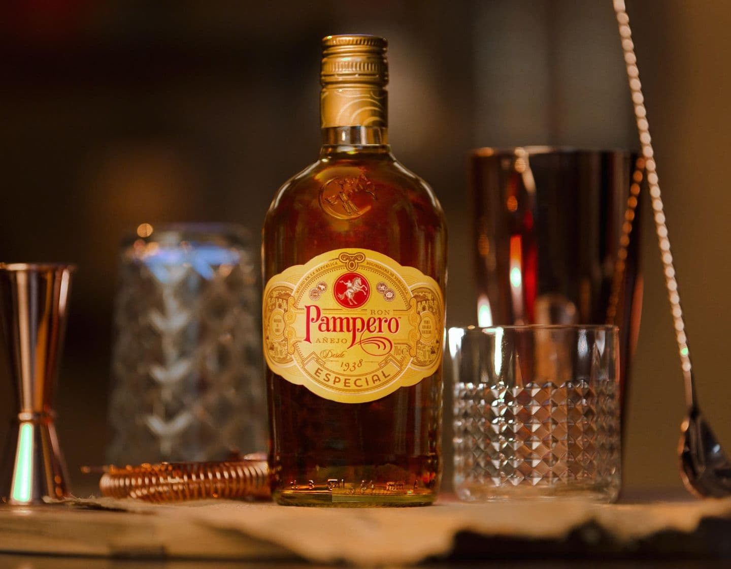 Eine Flasche Pampero Especial Rum neben einem Jigger mit zwei Cocktails im Hintergrund 