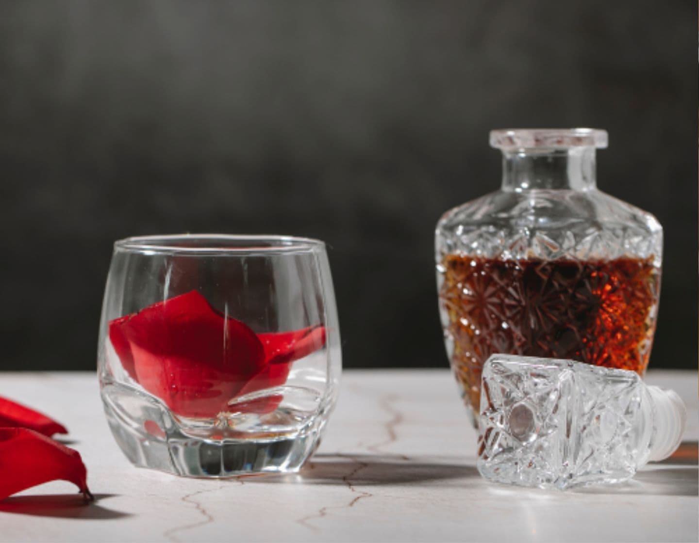 Un vaso y un decantador de brandy sobre una mesa. 