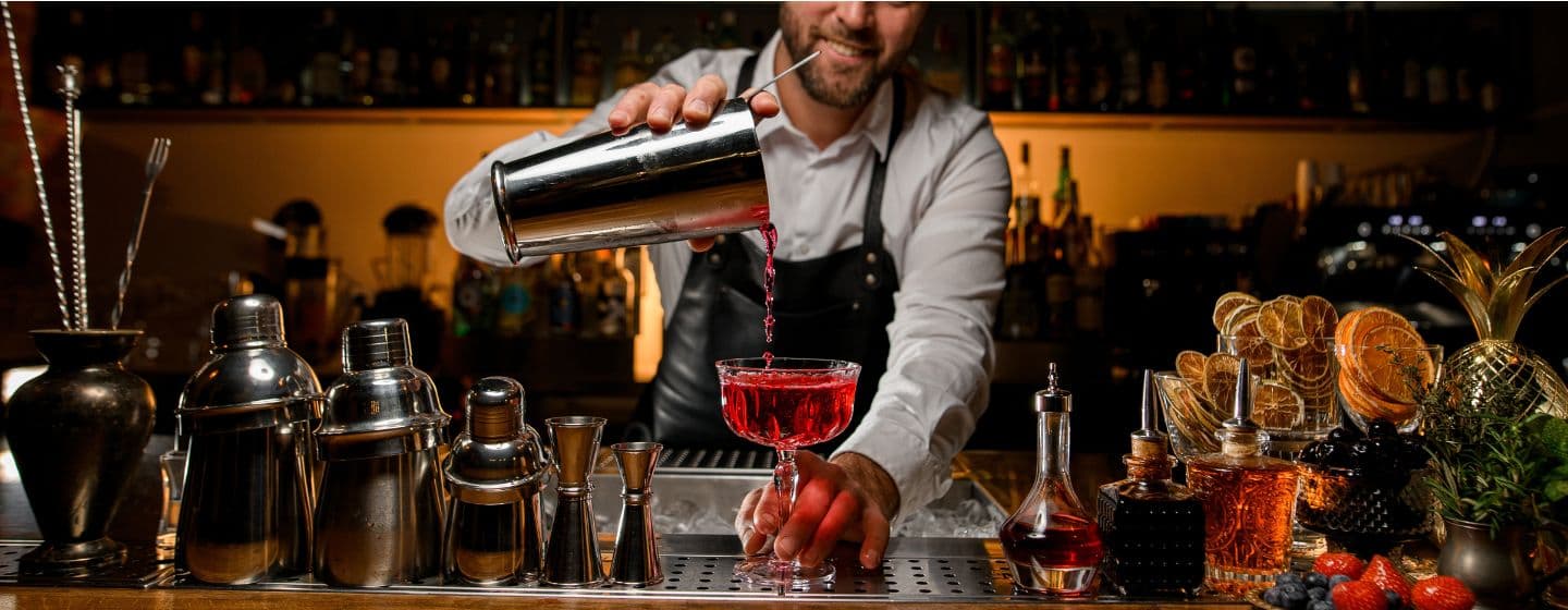 Imagem de um bartender fazendo um coquetél vermelho no bar 