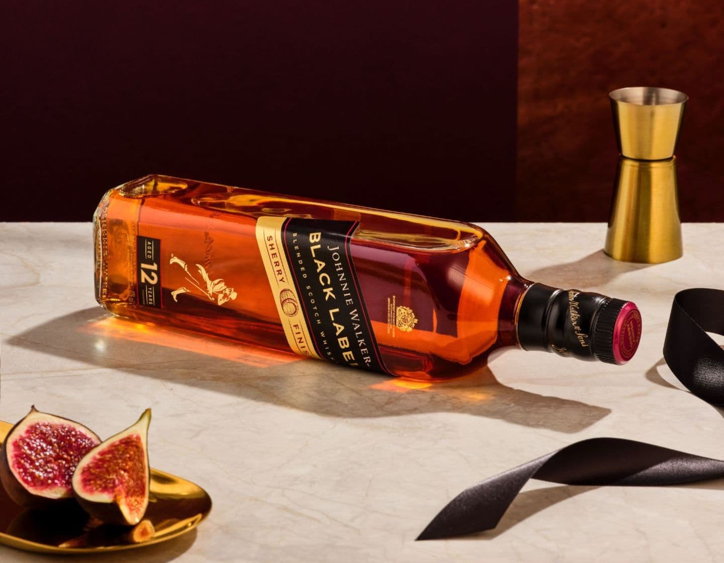 Johnnie Walker Black Label bottle and gold jigger on a white table