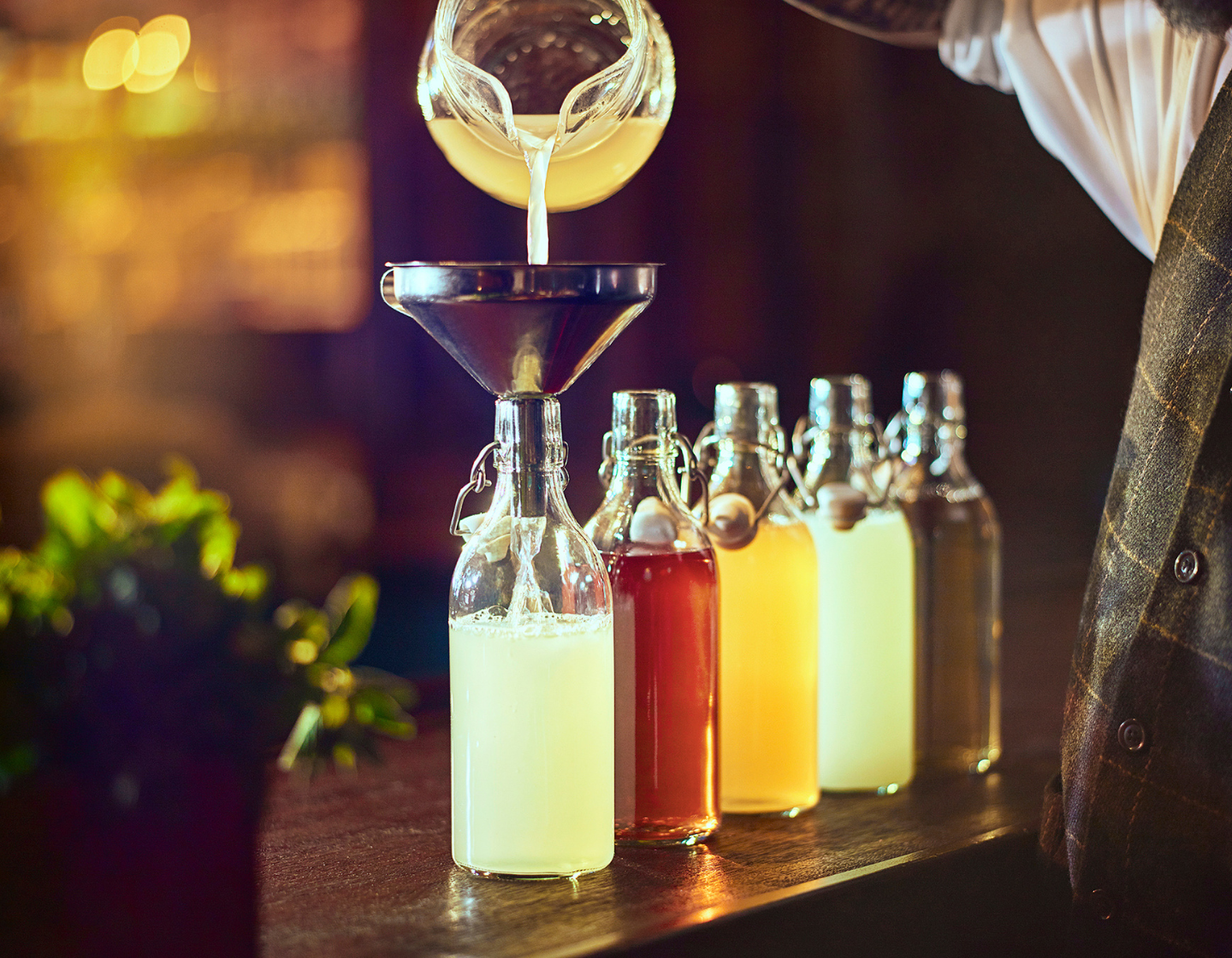 Batched cocktails being poured into bottles 