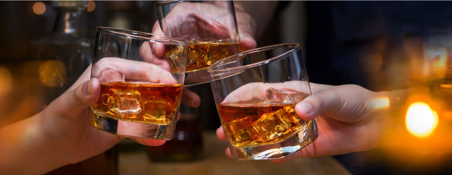 Imagem de pessoas com copos com whisky brindando