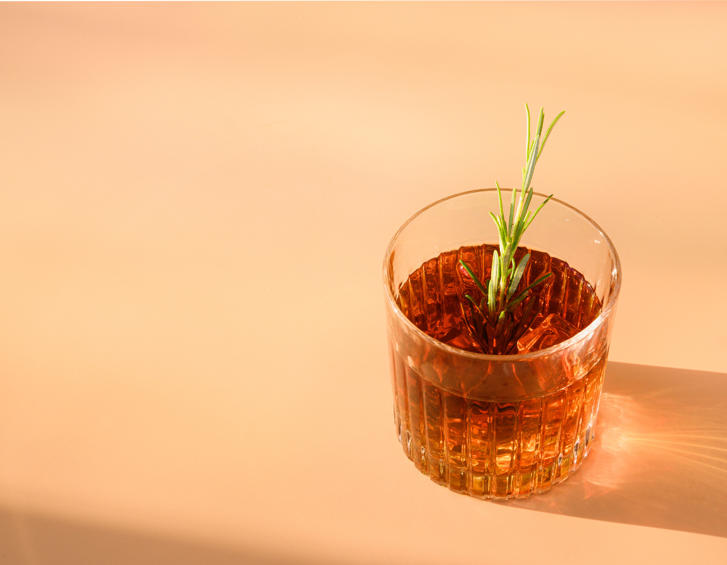   Glass of Whisky with ice and rosemary garnish 