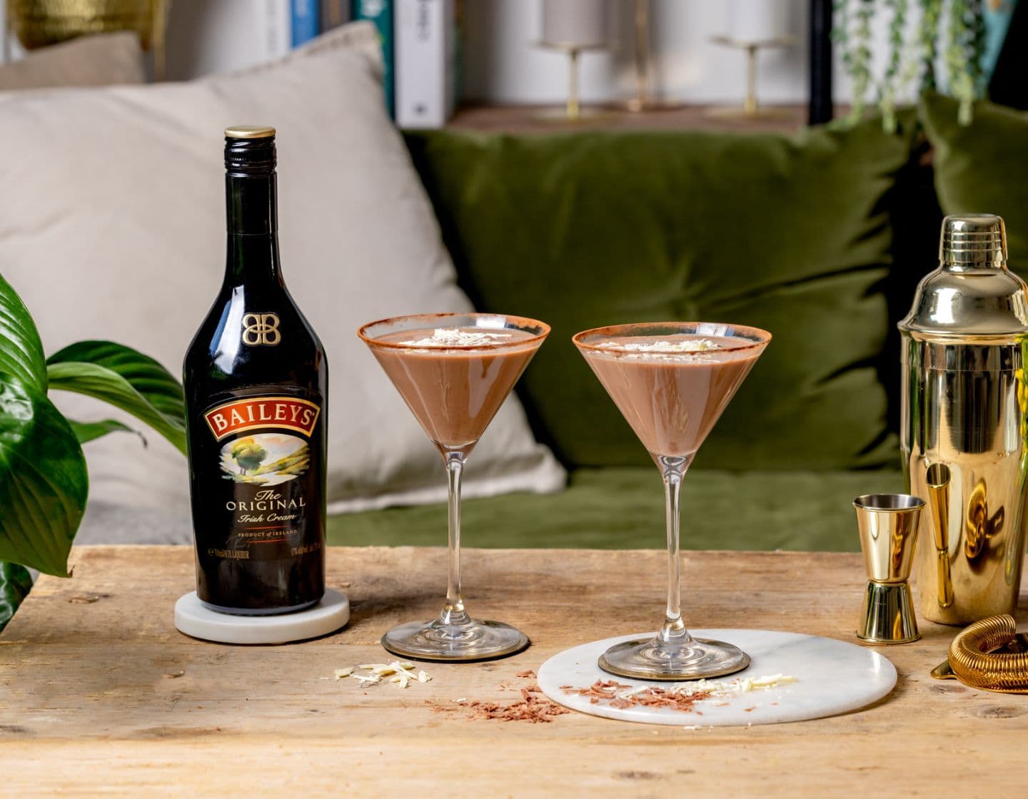 Bottle of Baileys next to two cocktails and cocktail shaker