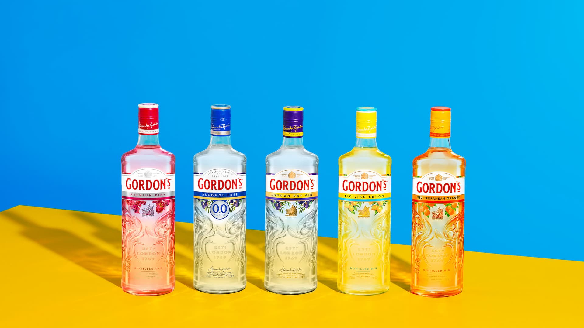 Seleção de garrafas de gin Gordon's em um fundo colorido