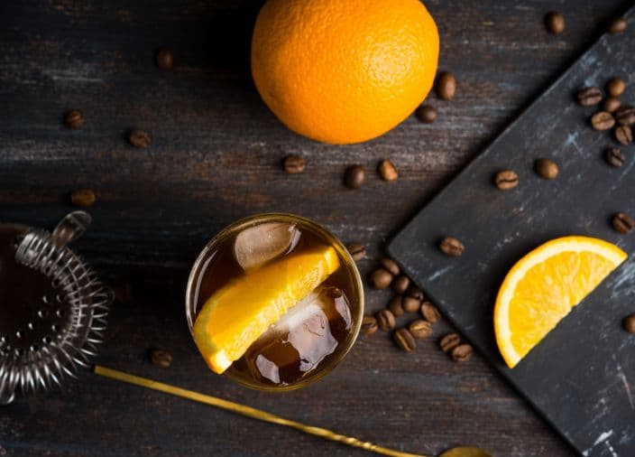 Cocktailvorbereitung mit Orangenscheiben und Kaffeebohnen 