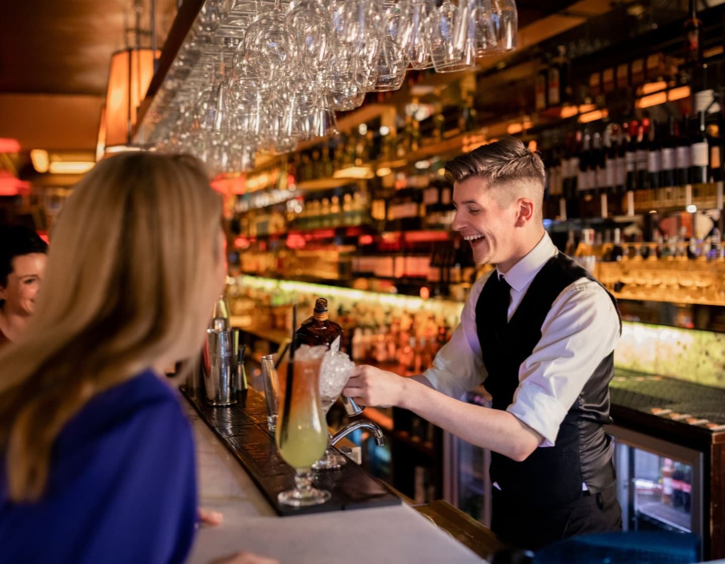Un bartender sonriente adorna un cóctel en un bar sofisticado