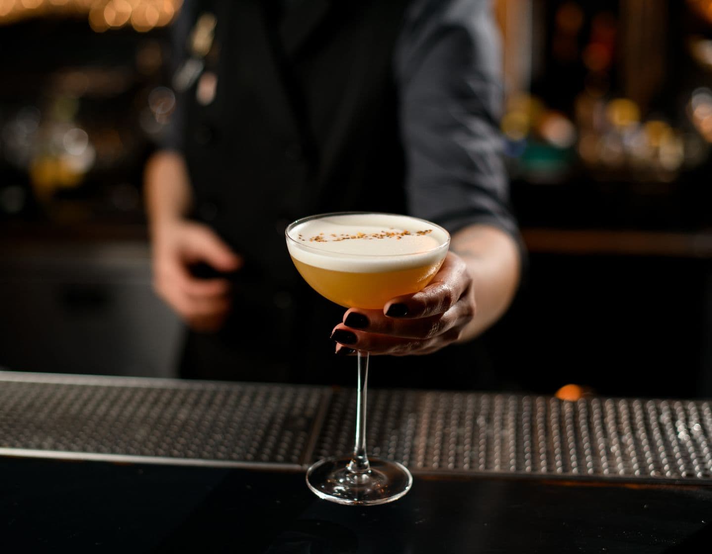 Bartender serving cocktail with garnish 