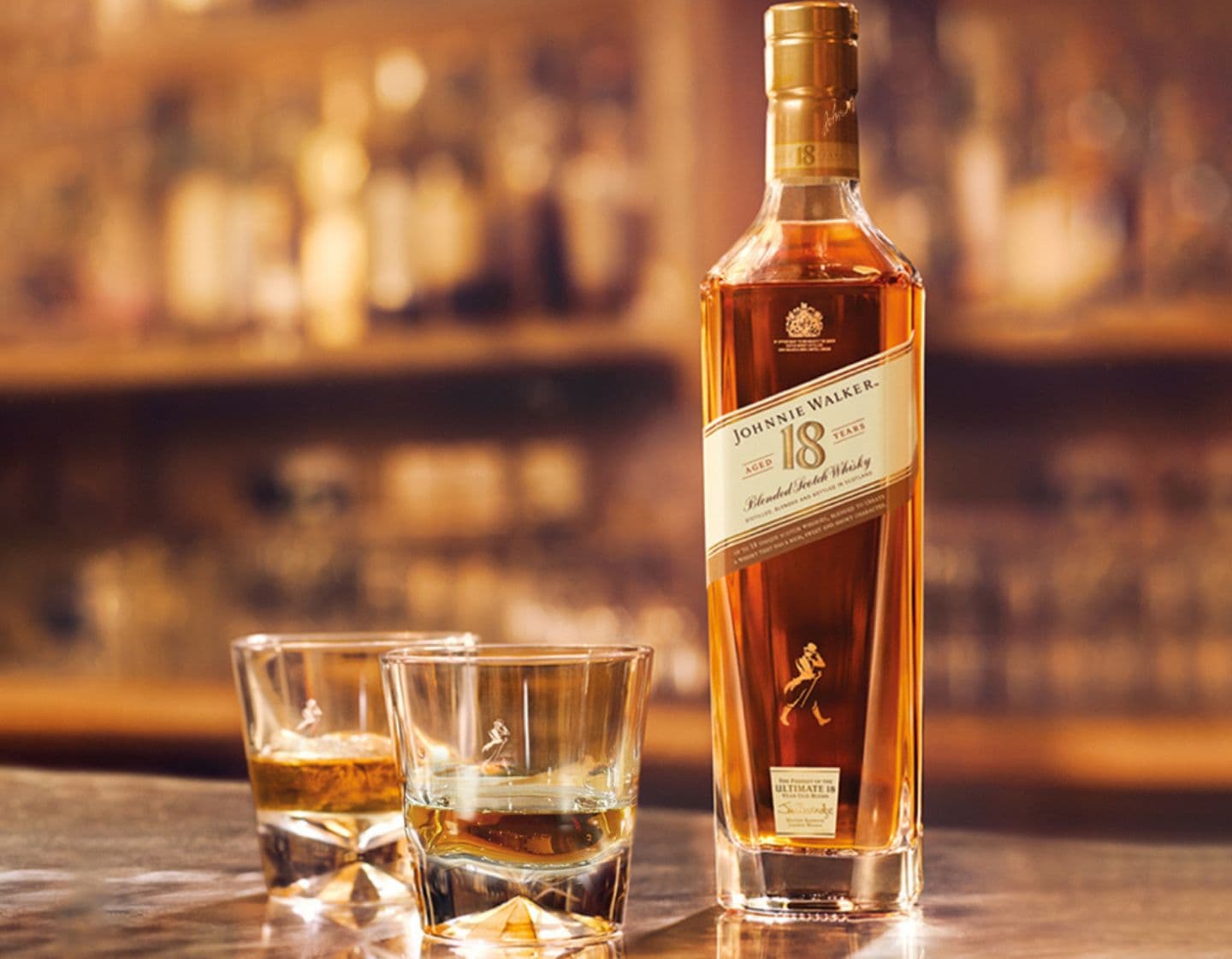 Botella de whisky Johnnie Walker Aged 18 Years junto a 2 vasos de whisky.