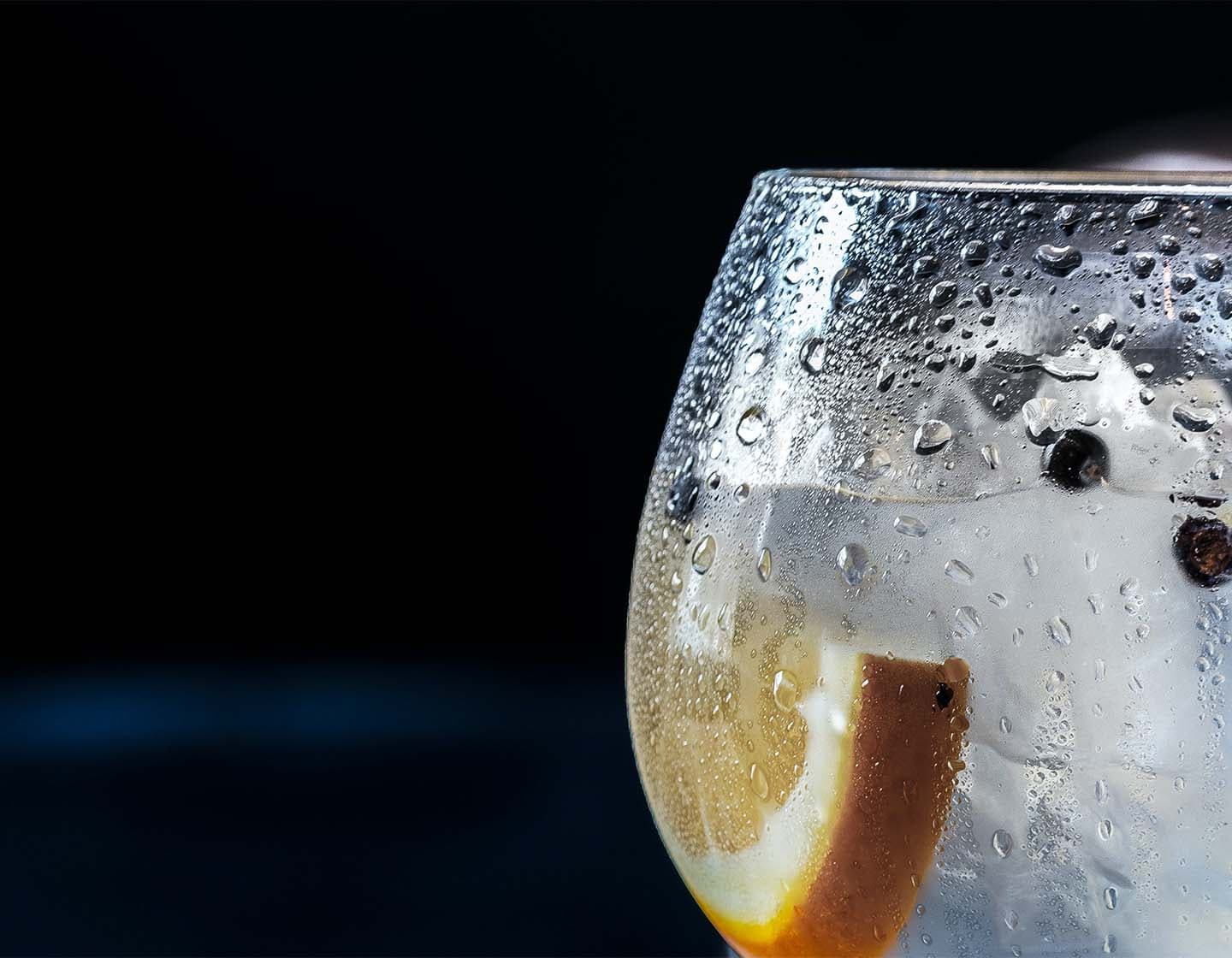 Extreme close-up of a filled gin glass with an orange slice.
