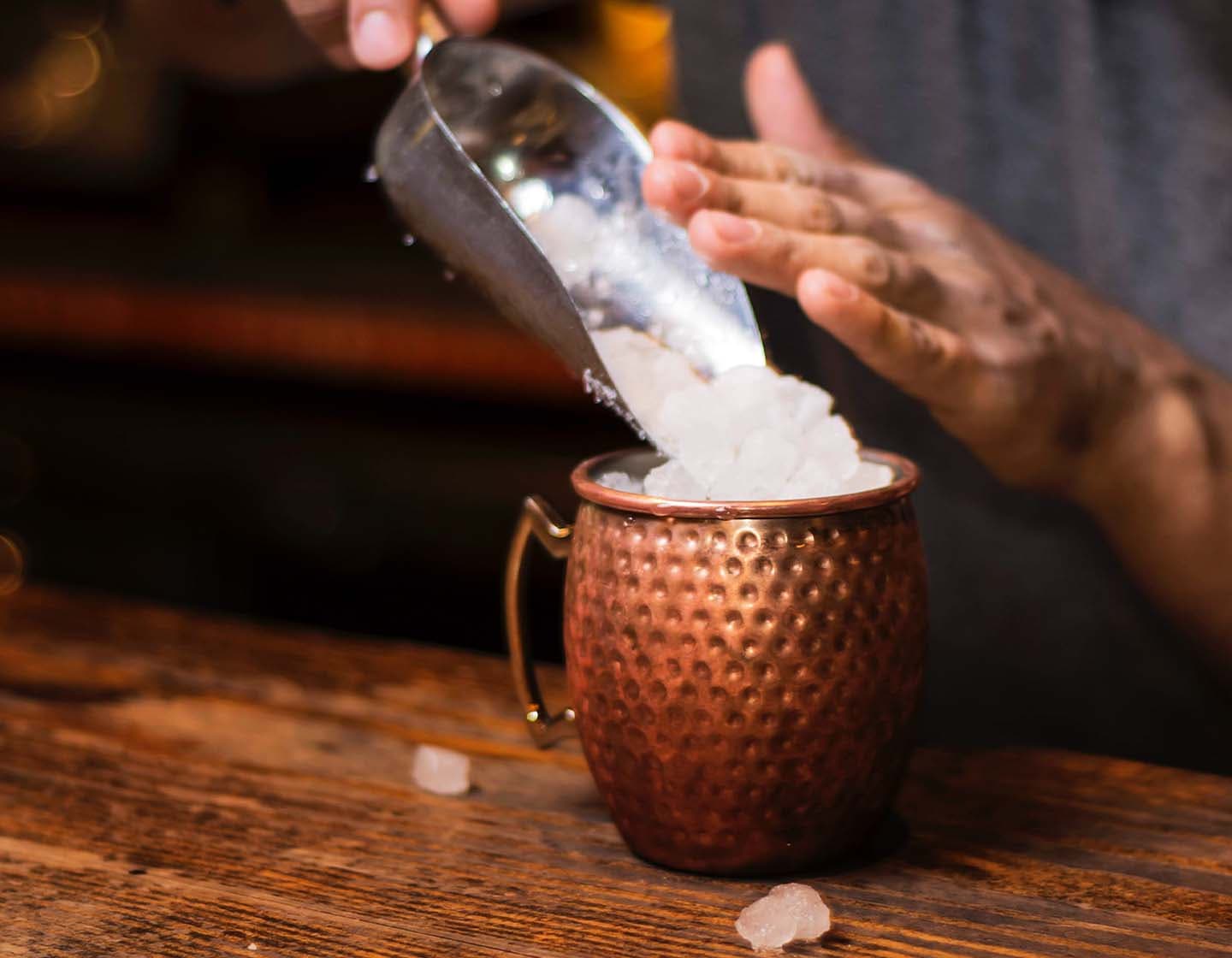 Crushed ice being scooped into a bronze cup. 