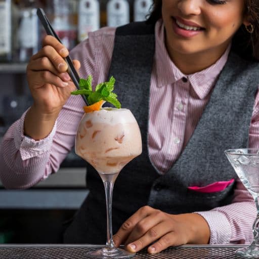Bartender adding a leafy garnish to a cocktail