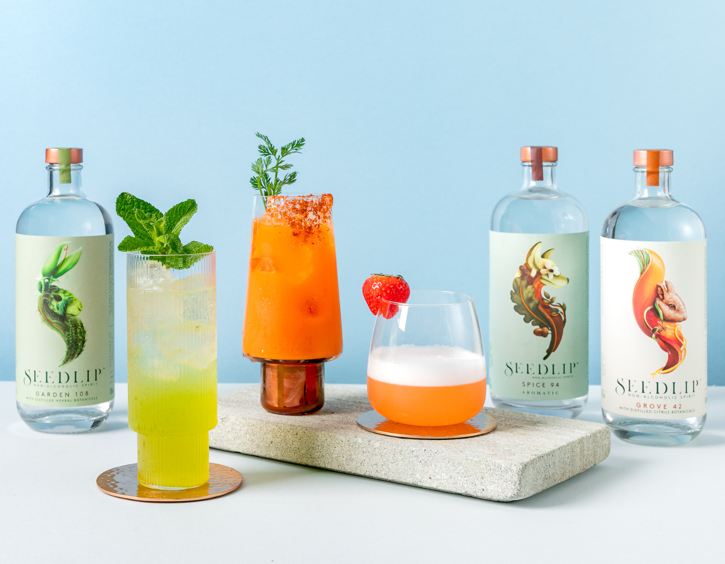 Three colourful cocktails surrounded by three different bottles of Seedlip non-alcoholic spirits.