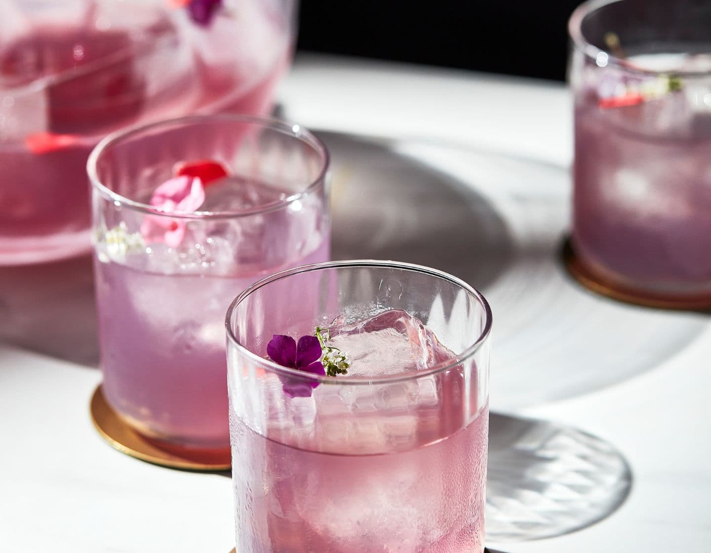 Purple cocktail serve with flower garnish
