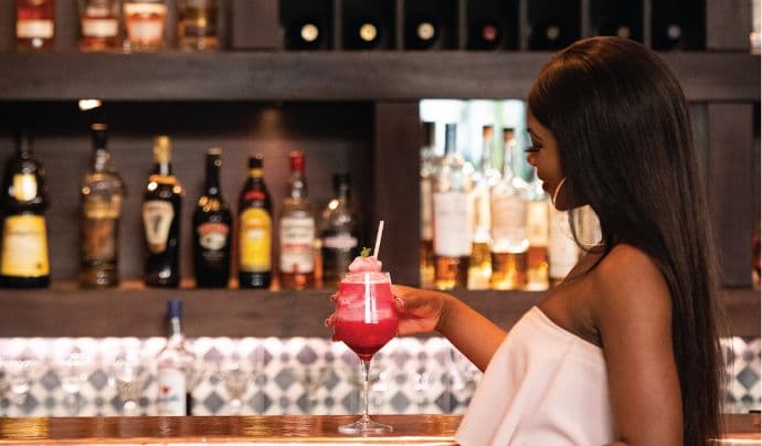 Customer holding a red cocktail in a bar setting.